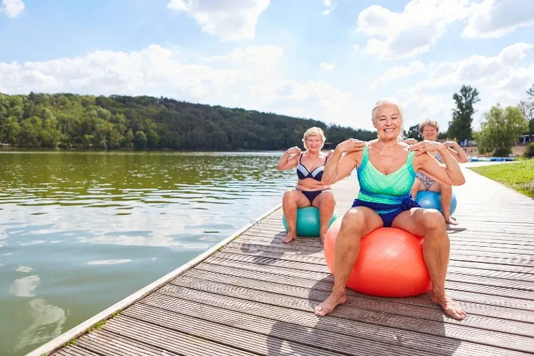 Gezond ouder worden door een gezonde leefstijl. Zoals deze 3 dames die op een bal balansoefeningen doen.