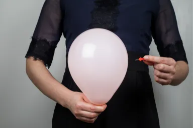 Een opgezette buik tijdens de overgang. Een ballon die wordt doorgeprikt