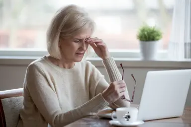 Vrouw zit vermoeid achter haar laptop. Vermoeidheid tijdens de overgang.